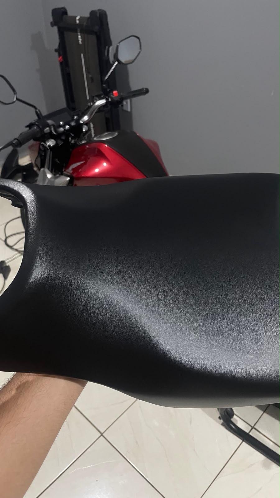 Banco tratado em primeiro plano, com a moto vermelha ao fundo