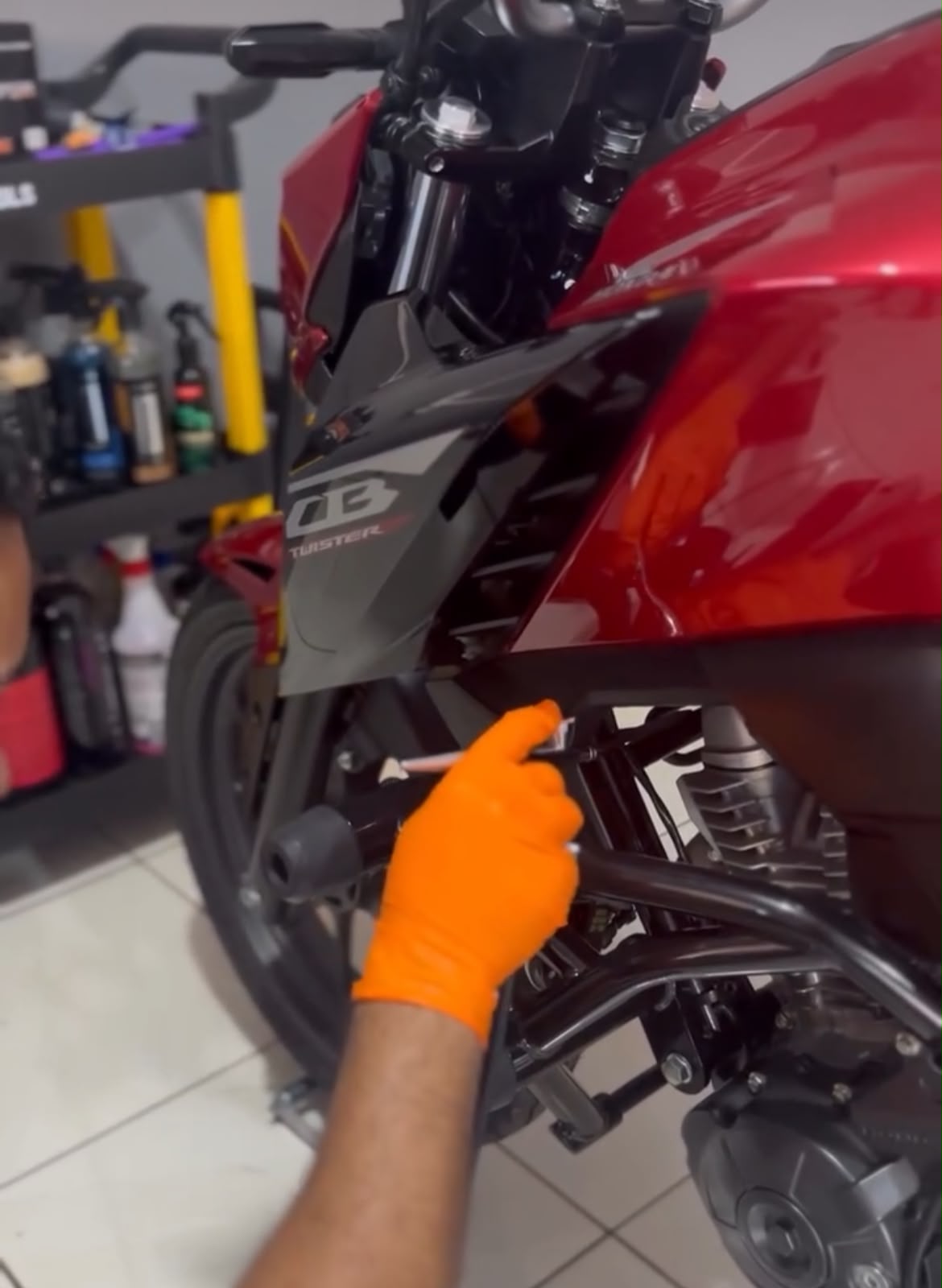 Aplicação do vitrificador na carenagem de uma Honda CB Twister, com luva e aplicador